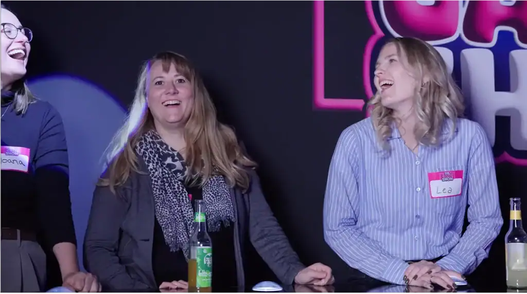 Zwei Spielerinnen lachen bei „The Gameshow Hamburg“ am Buzzerpult – lockere Stimmung und echtes Team-Event-Feeling in der Live-Gameshow